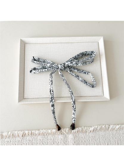 White paisley skinny scarf tied in a wide bow