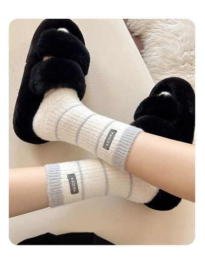 Gray striped crew socks styled with black fuzzy slippers