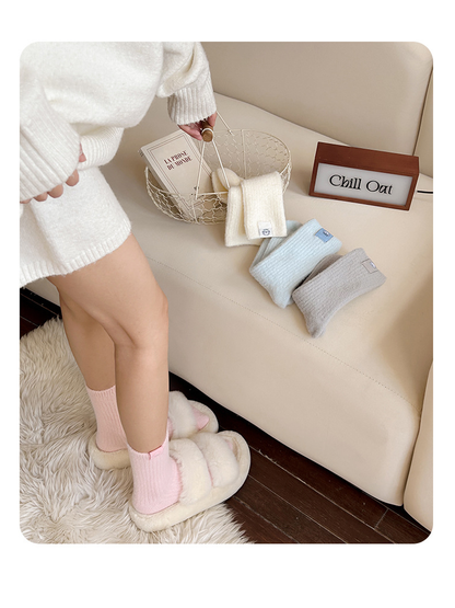 Light Pink ribbed crew socks worn with plush slippers beside folded Ivory, Light Blue, and Light Gray colors