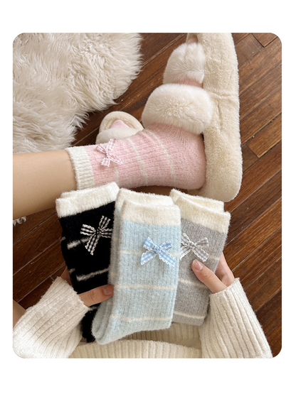 Pink striped crew sock worn with slippers beside folded Black, Light Blue and Light Gray styles