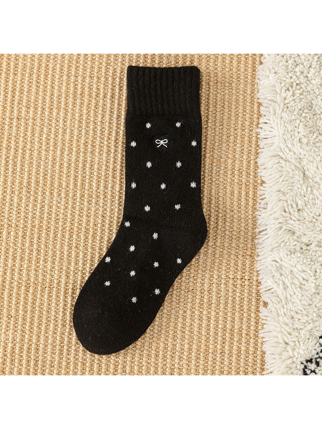 Black dot-pattern crew sock with ribbed cuff and bow patch