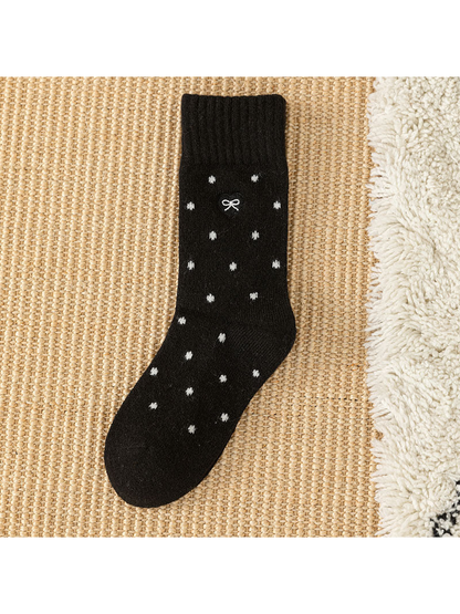 Black dot-pattern crew sock with ribbed cuff and bow patch