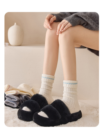 Ivory Blue ribbed socks worn with black slippers in a seated view