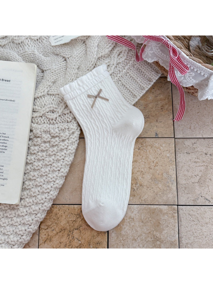 White ankle sock with ruffled cuff, ribbon bow, and pointelle texture