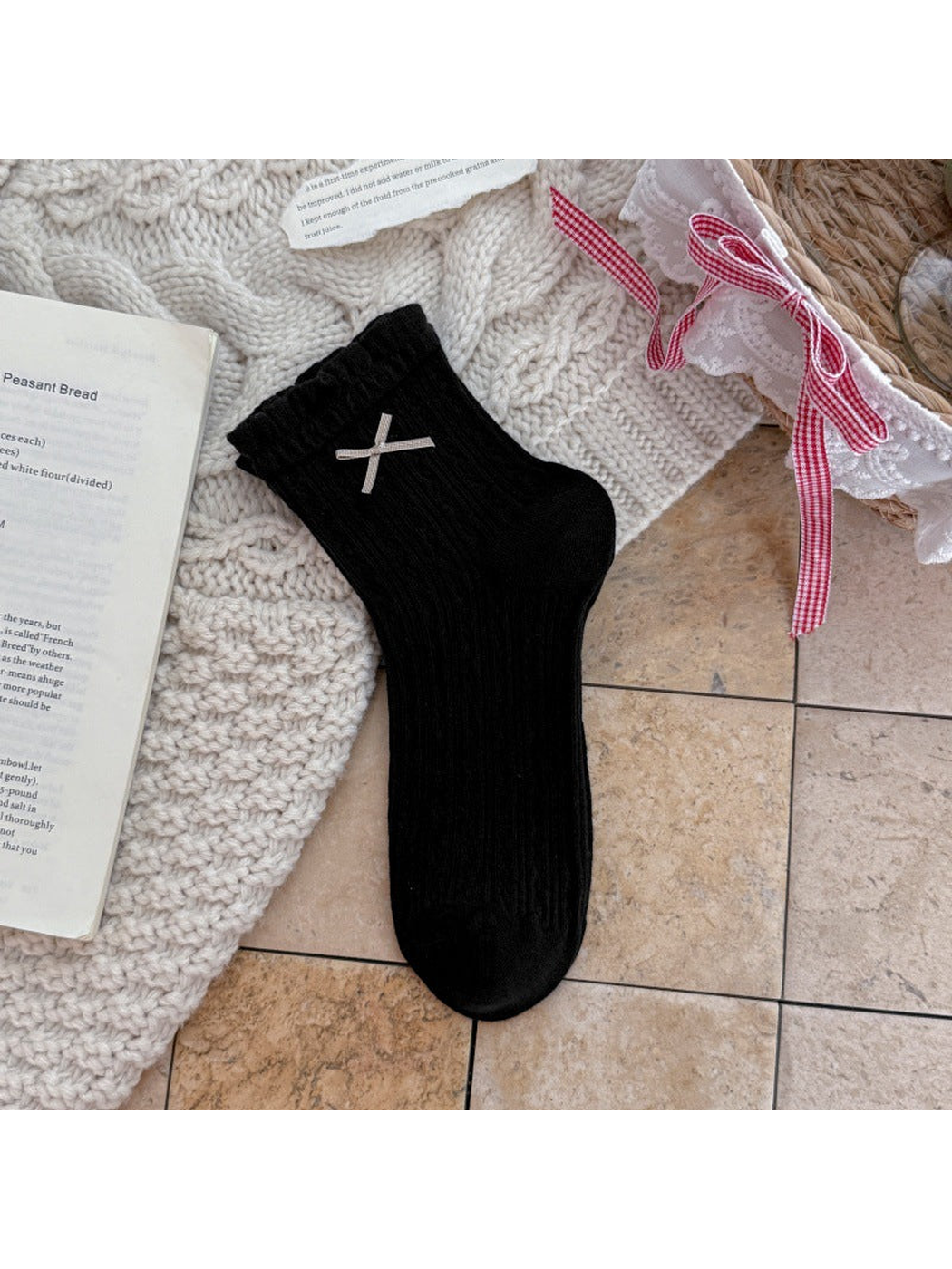 Black ankle sock with ruffled cuff, ribbon bow, and pointelle texture
