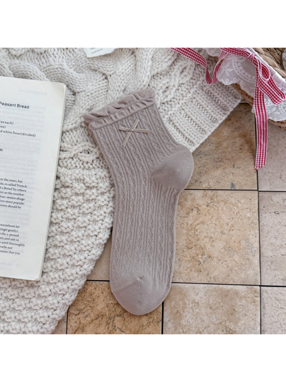 Greige ankle sock with ruffled cuff, ribbon bow, and pointelle texture