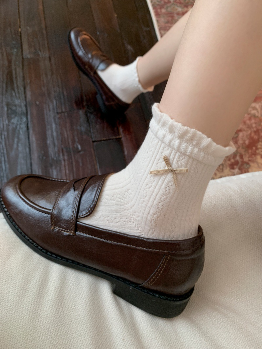 White ankle socks with ruffled cuffs and ribbon bows worn with brown loafers