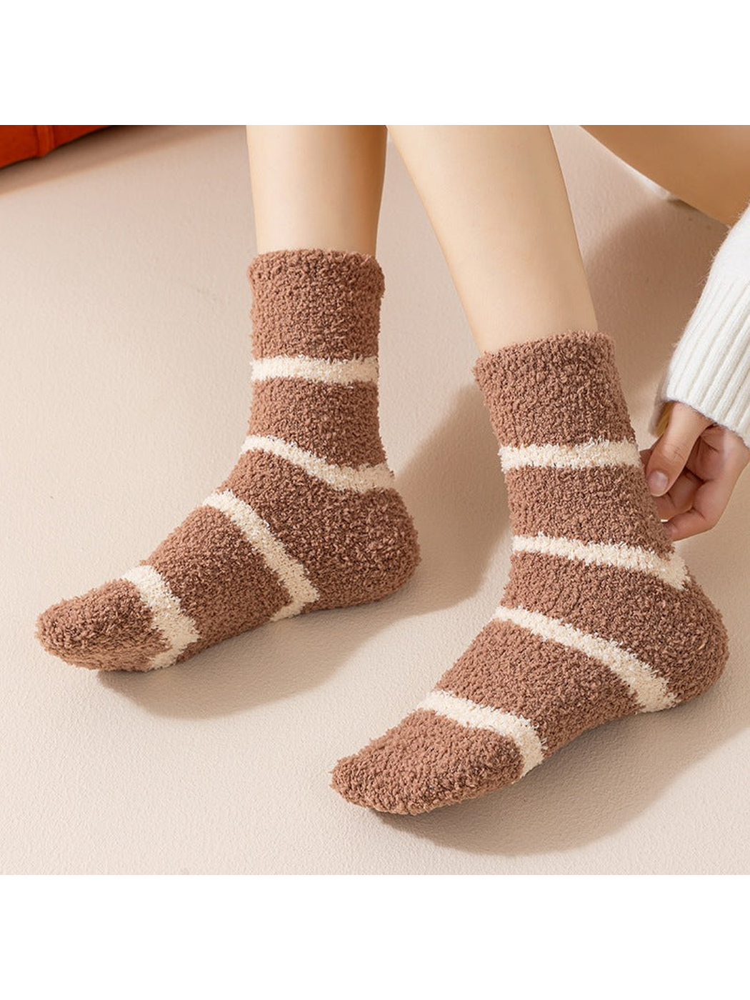 Brown striped fuzzy crew socks worn while seated