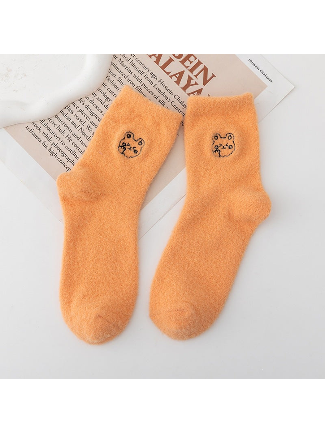 Orange fuzzy crew socks with small outlined animal-face motifs