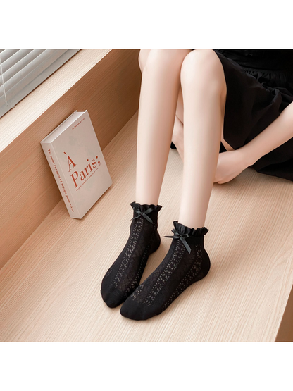 Black Bow ankle socks worn in a seated indoor setting