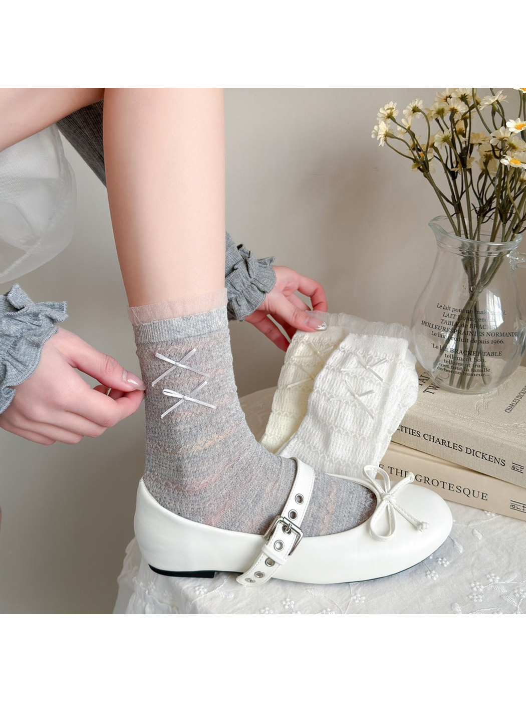 Light gray openwork socks with ribbon bows styled with white buckle shoes
