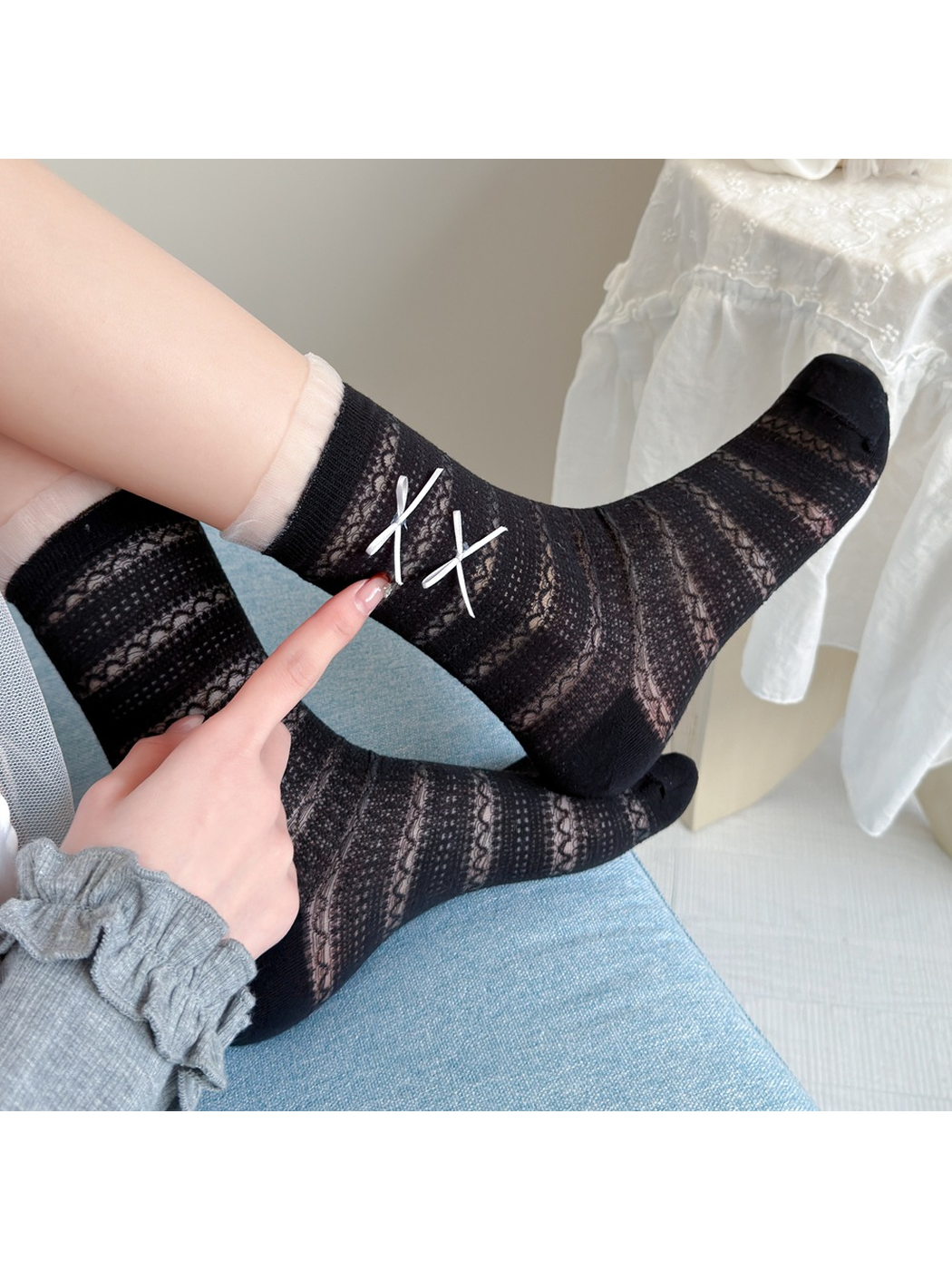 Close-up of black openwork socks with sheer ruffle cuffs and white ribbon bows