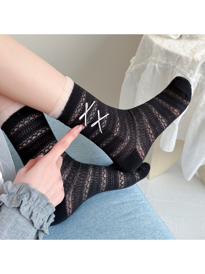 Close-up of black openwork socks with sheer ruffle cuffs and white ribbon bows