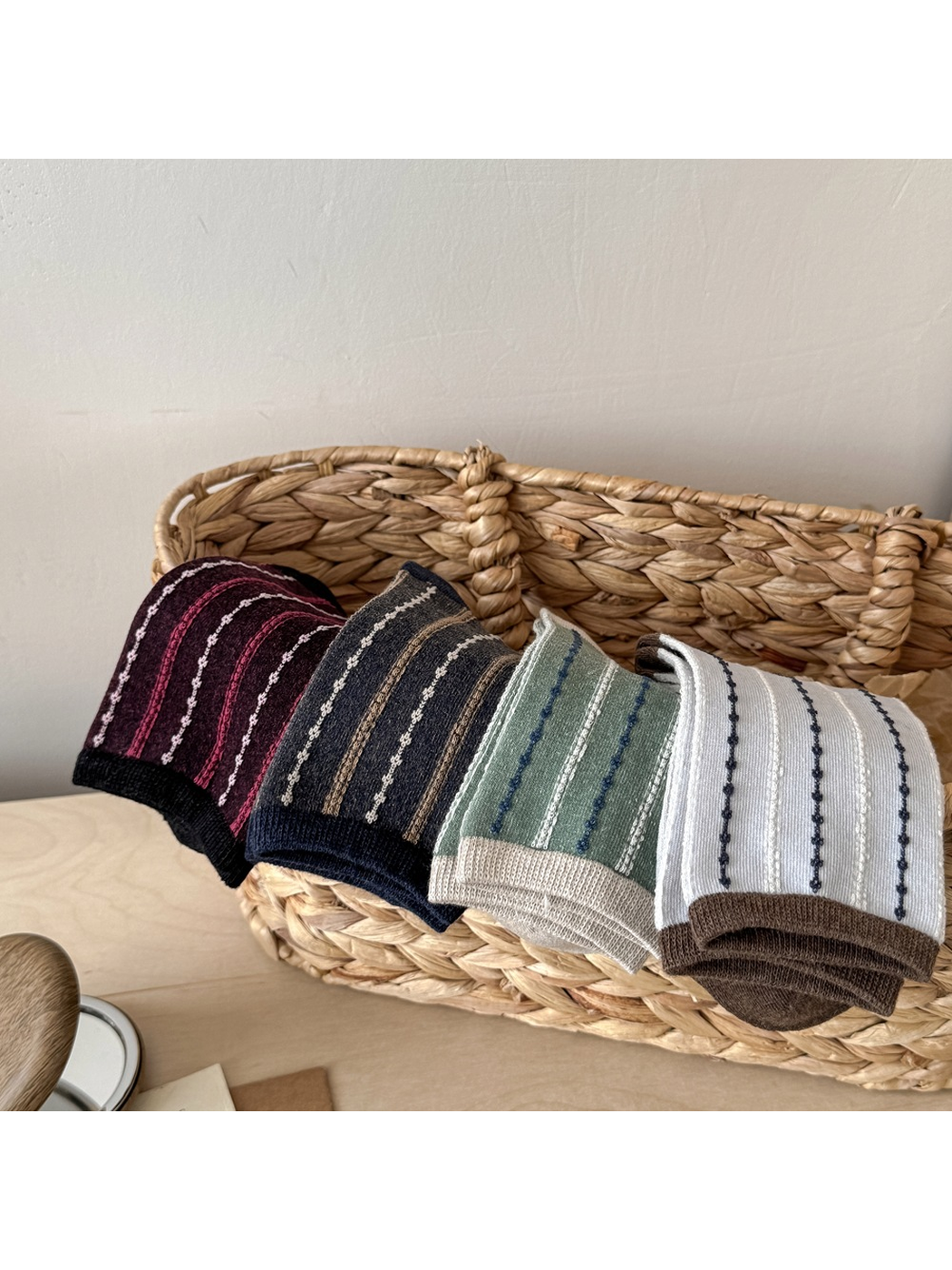 Four striped sock colors folded over a woven basket