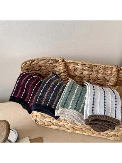 Four striped sock colors folded over a woven basket