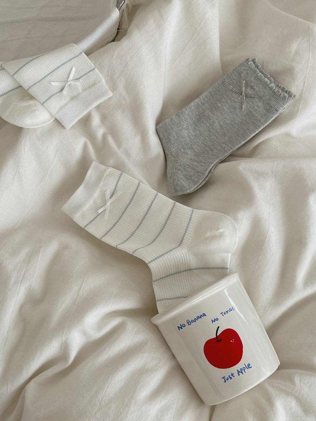 Bow and Striped Bow crew socks arranged on white bedding