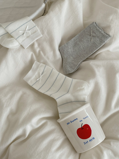 Bow and Striped Bow crew socks arranged on white bedding