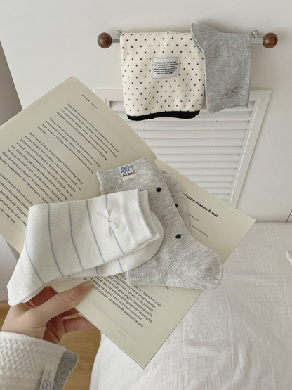 Bow, Polka Dots, Striped Bow, and Sheep Label crew sock styles displayed with an open book