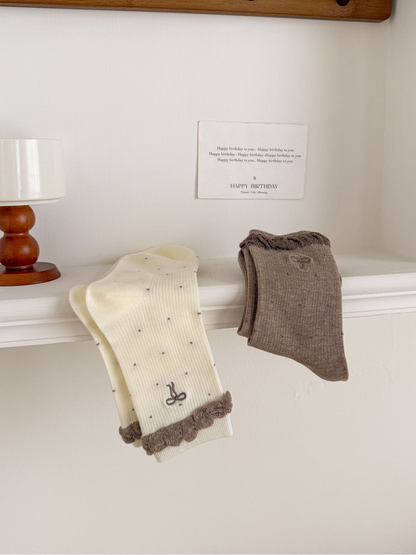 Ivory and Coffee dotted socks draped together to show bow and ruffled cuff details