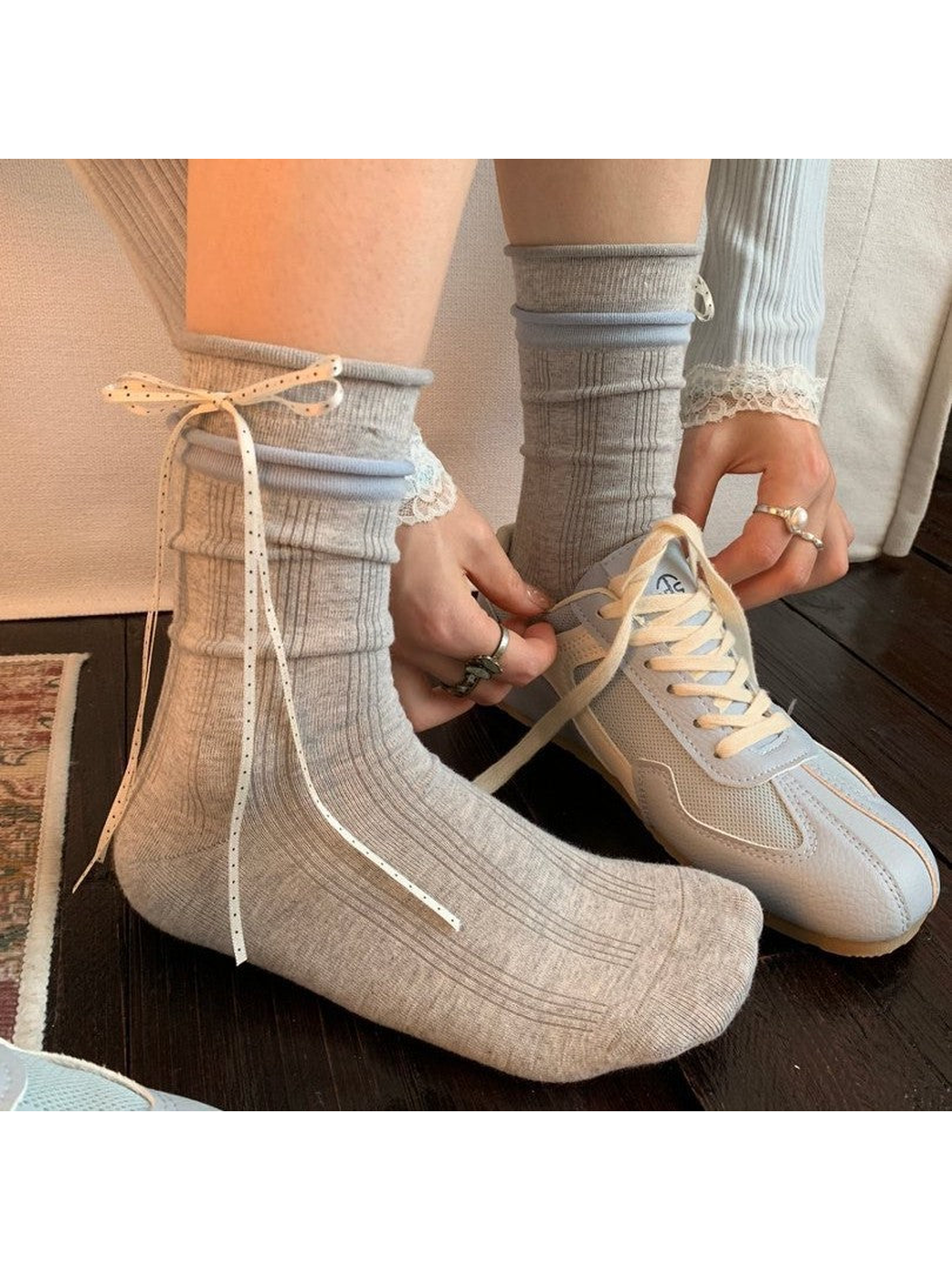 Light gray ribbed crew socks with ribbon bows worn beside a neutral sneaker