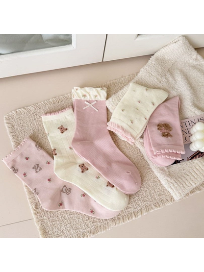 Pink and ivory crew socks arranged flat and folded to show their patterns and cuffs