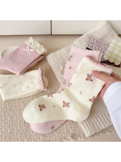 Close-up of ivory ribbed crew socks with teddy bear and floral motifs