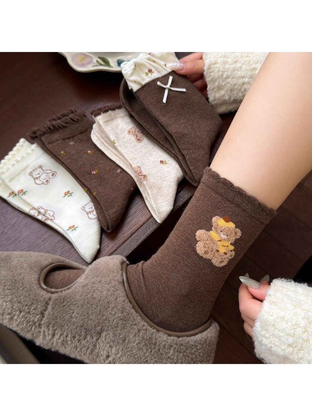 Teddy Applique socks worn with brown fuzzy-look footwear beside four folded styles
