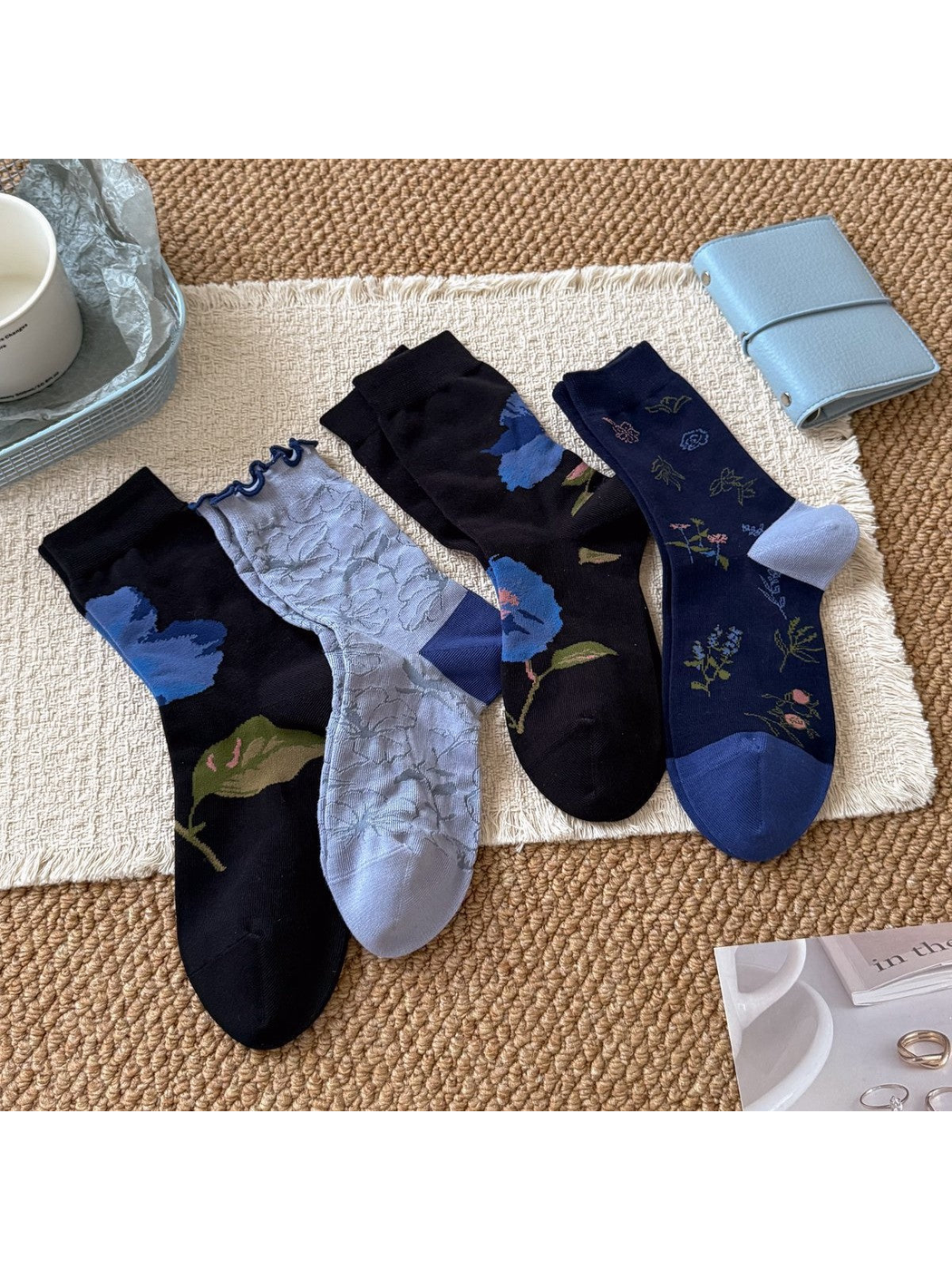 Four floral crew sock styles arranged together on a textured rug