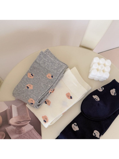 Folded Light Gray, Ivory and Navy socks with repeating bear-face motifs