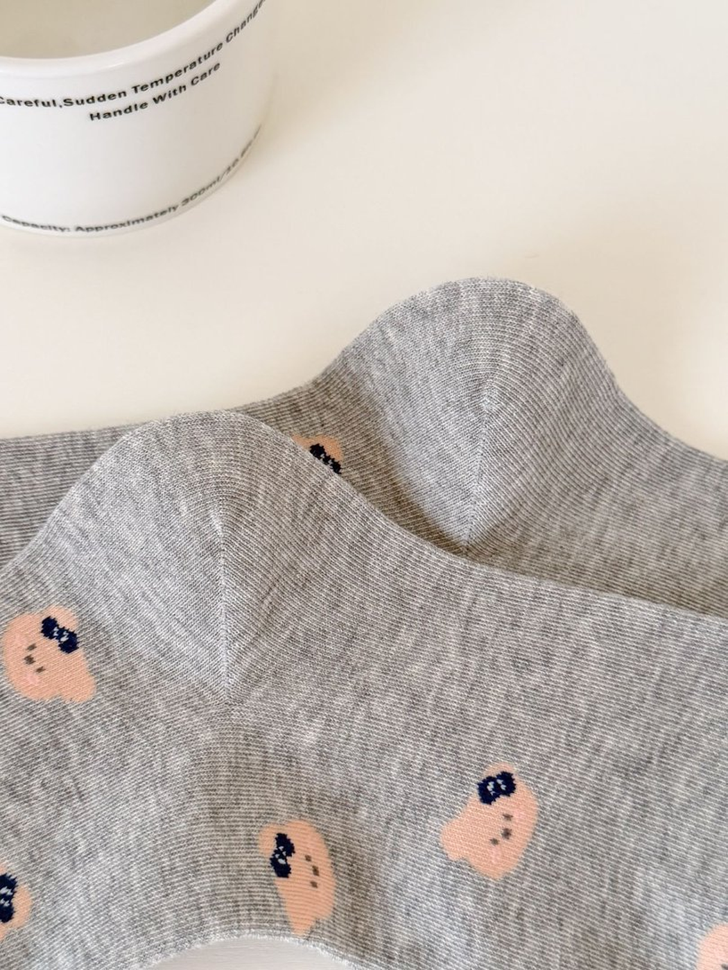 Close-up of Light Gray sock knit and repeating bear-face motif