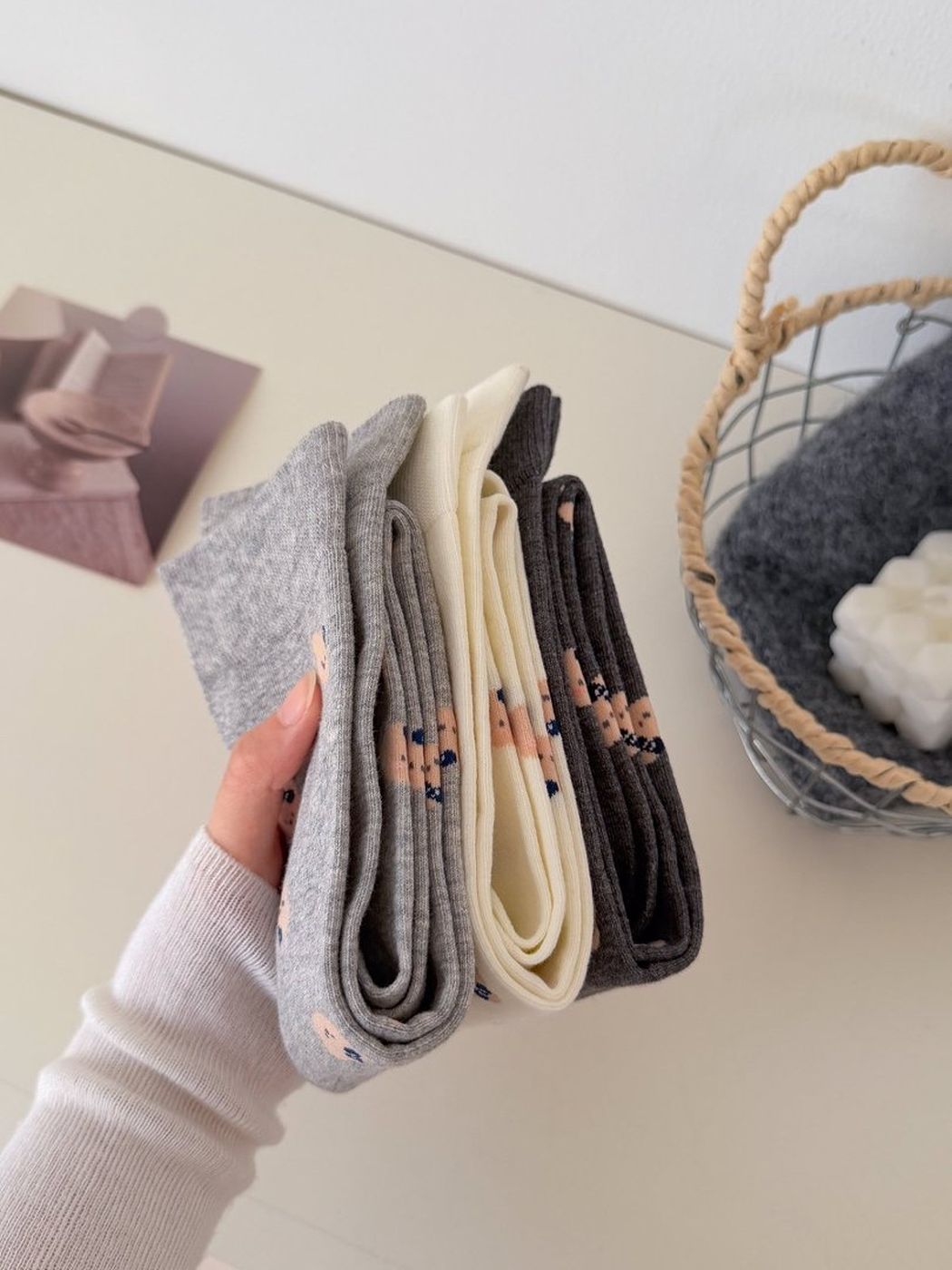 Folded Light Gray, Ivory and Dark Gray bear-face socks viewed from the side