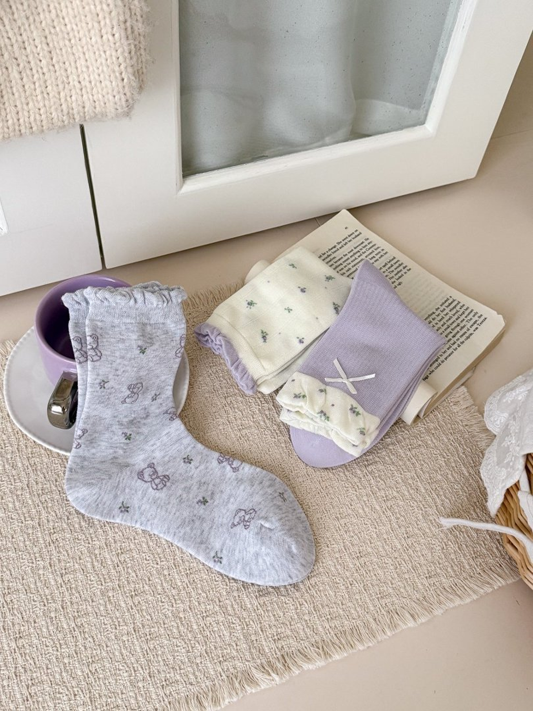 Heather gray outlined-bear socks displayed with folded ivory and lavender styles