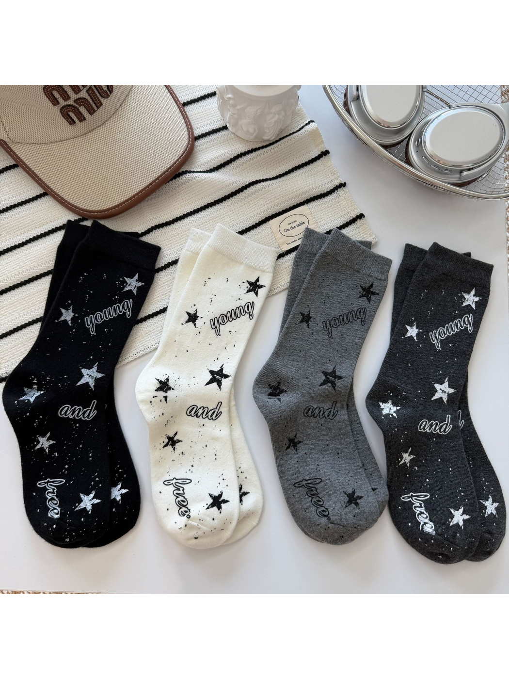 Black, ivory, dark gray and light gray crew socks with stars, speckles and script lettering