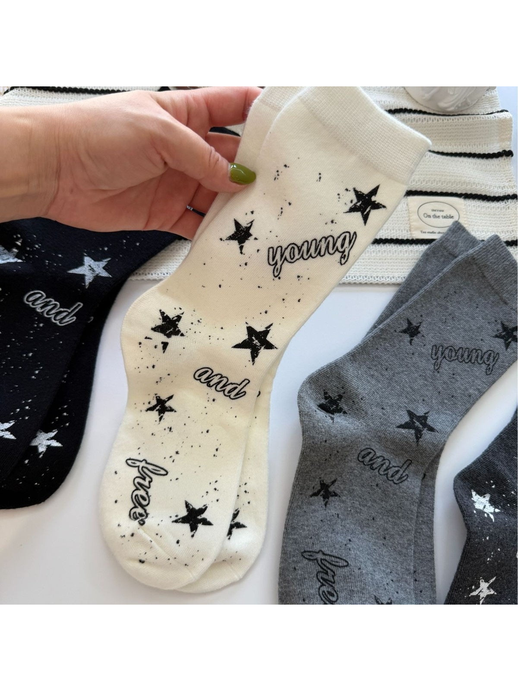 Ivory star-print crew socks held beside black and gray color options