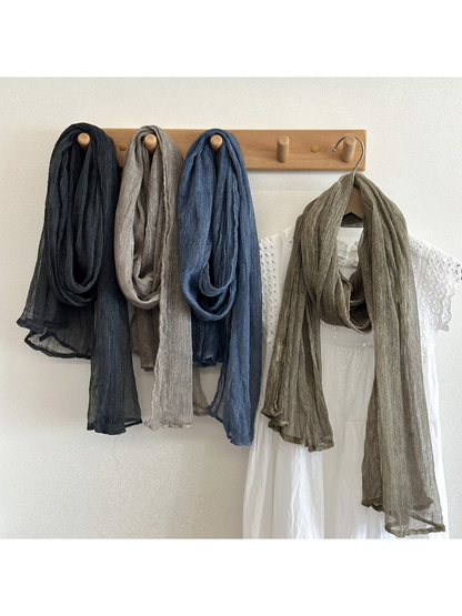 Black, gray, blue and green crinkled scarves displayed on a wall rack