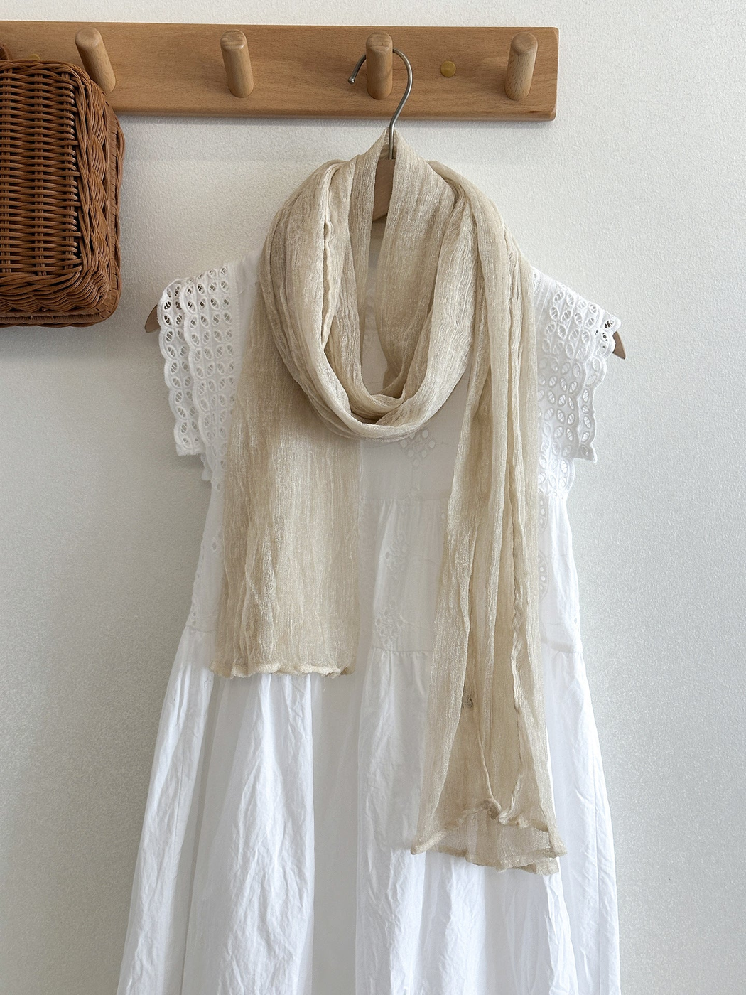 Cream crinkled scarf draped over a white eyelet dress