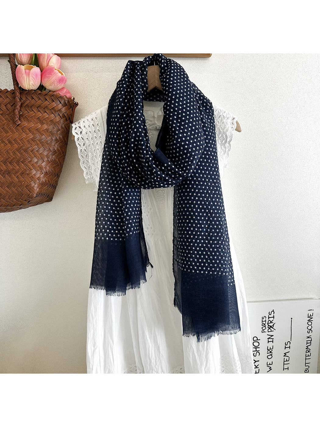Navy polka dot scarf styled over a white dress