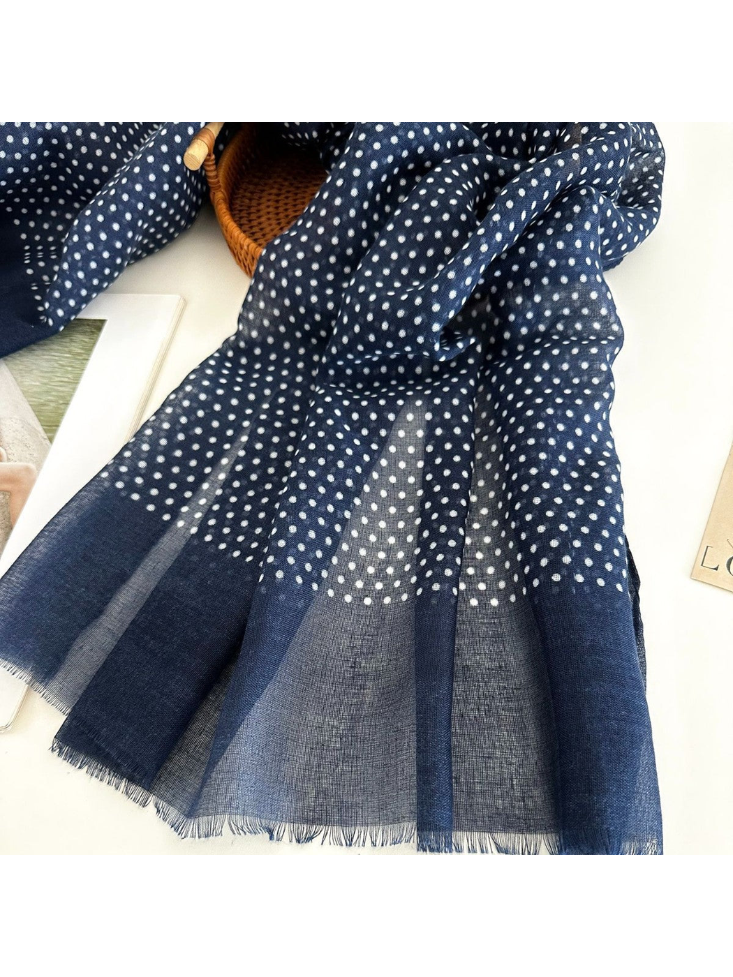 Close-up of navy polka dot pattern, plain border and fringed edge