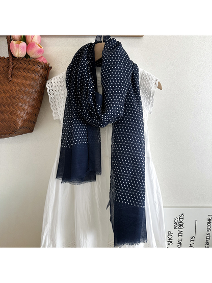 Navy polka dot scarf loosely draped over a white dress
