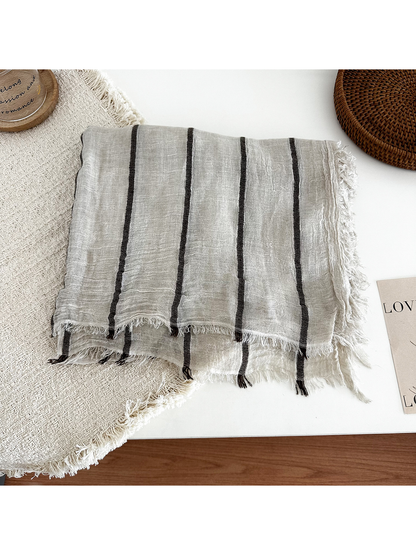Khaki striped scarf folded to show its crinkled texture and fringed edges