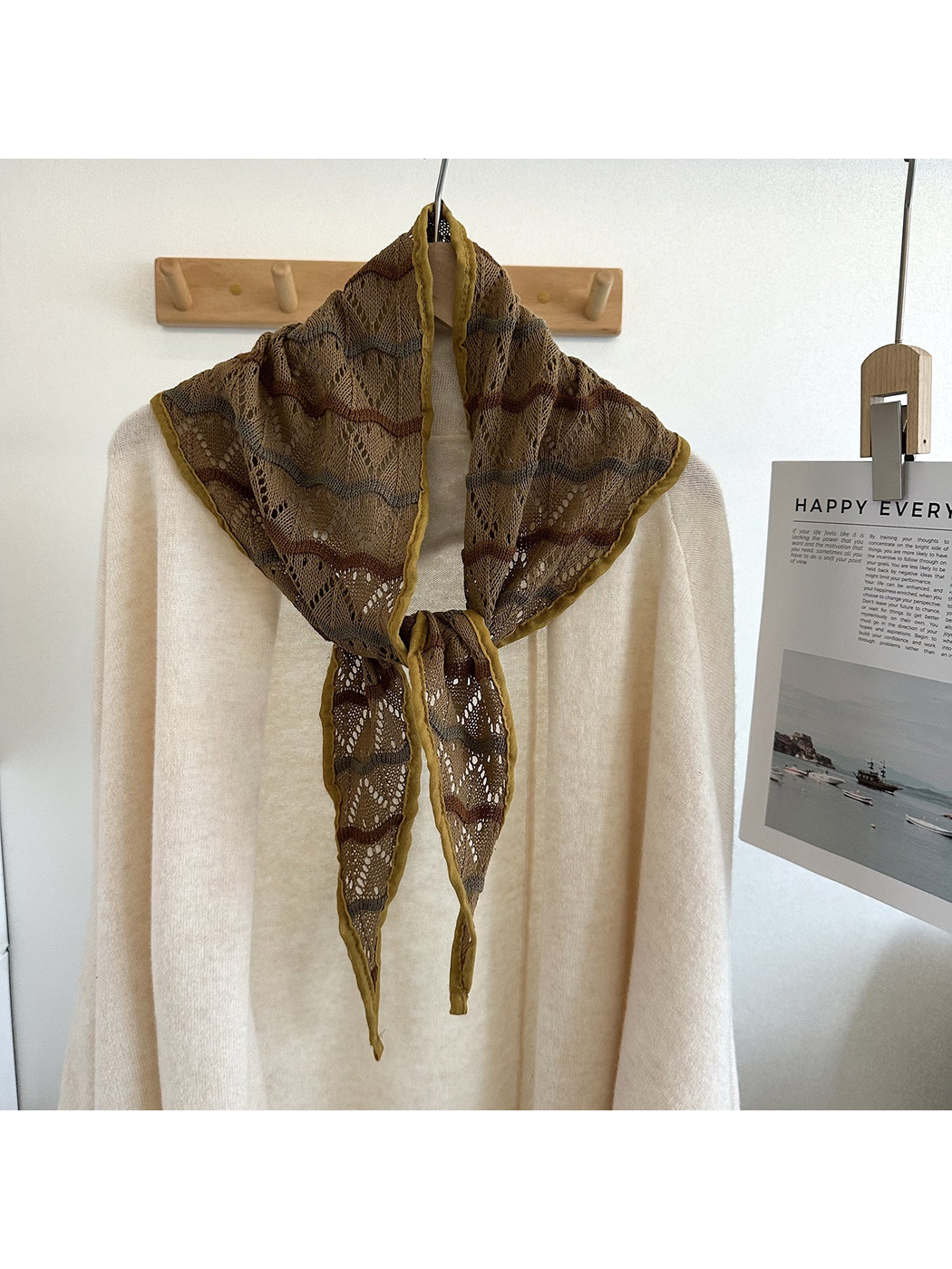 Coffee openwork triangle scarf tied over an ivory sweater