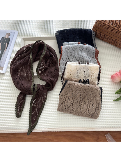 Multiple color variations of the openwork tapered scarf arranged with a Dark Brown scarf tied beside them