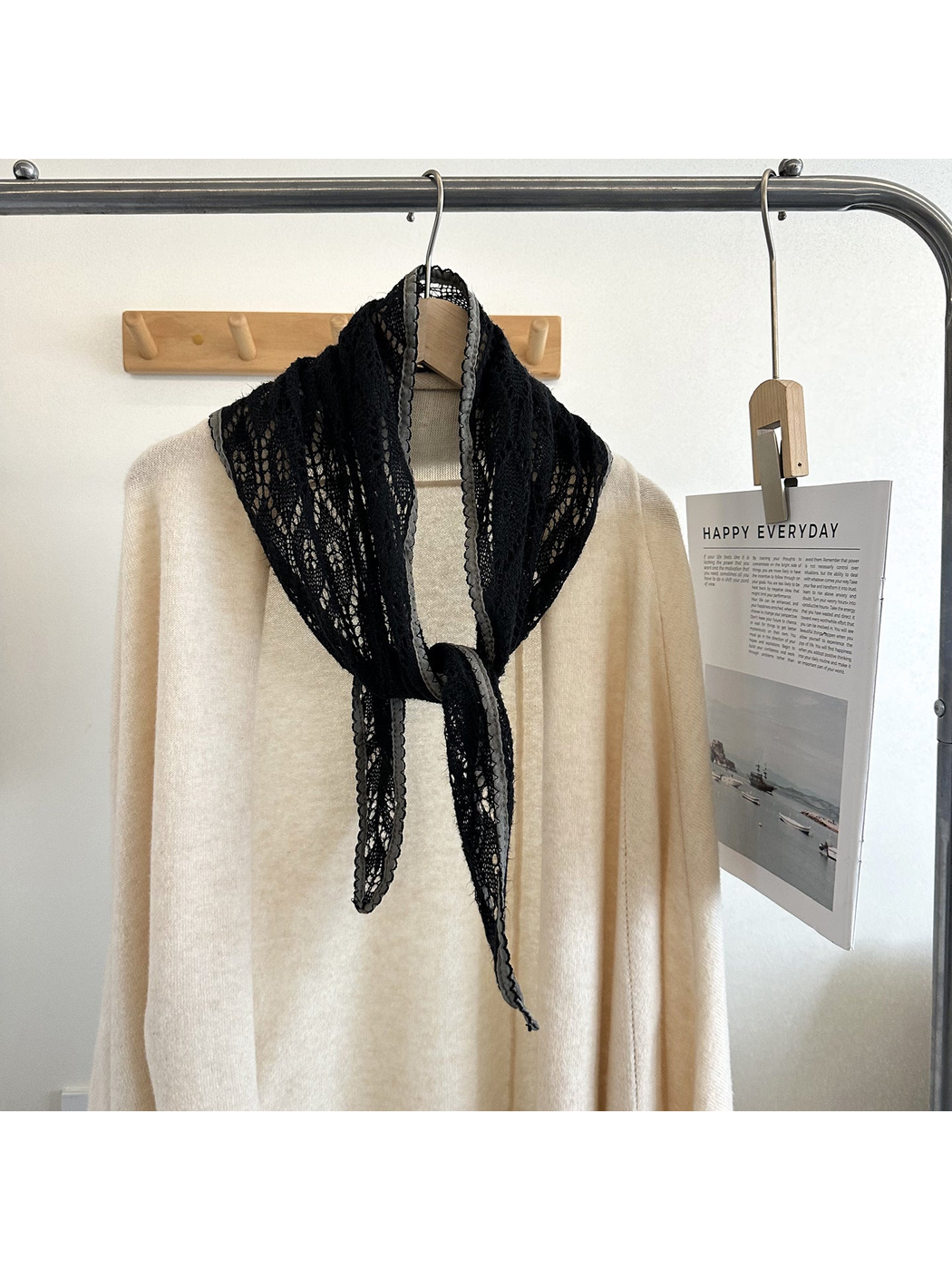 Black openwork tapered scarf with gray scalloped trim tied over a cream top