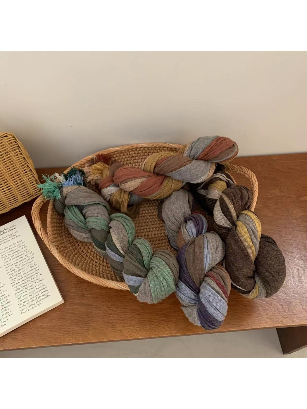 Multiple multicolor scarves loosely knotted in a woven tray