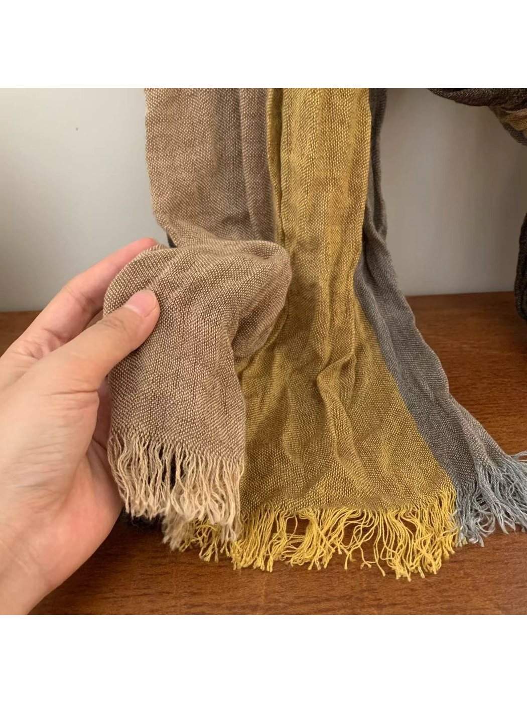 Close-up of the crinkled weave and fringed scarf edges in taupe, mustard and gray