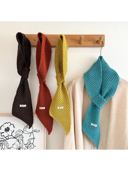 Four openwork pull-through scarves hanging on a wooden rack