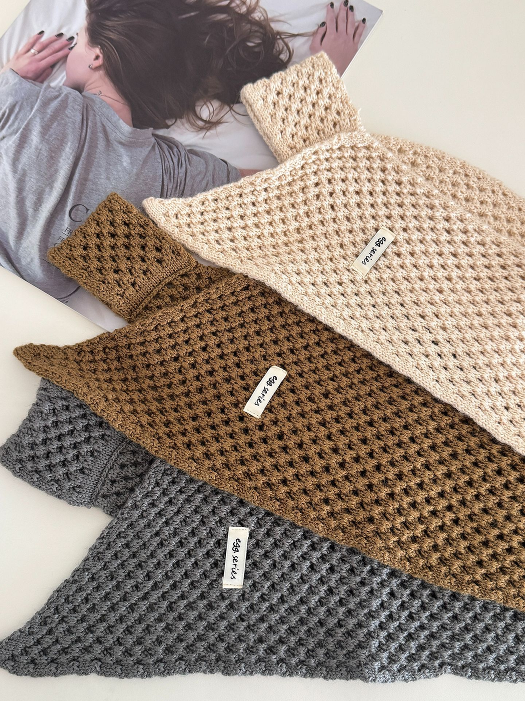 Close-up of cream, coffee and dark gray openwork scarves arranged on a tabletop