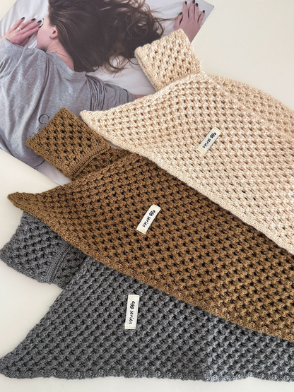 Close-up of cream, coffee and dark gray openwork scarves arranged on a tabletop