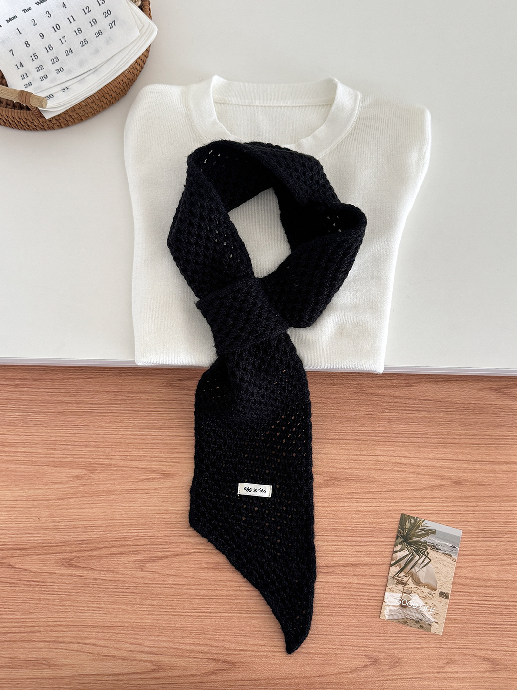 Black openwork pull-through scarf displayed with a folded white top
