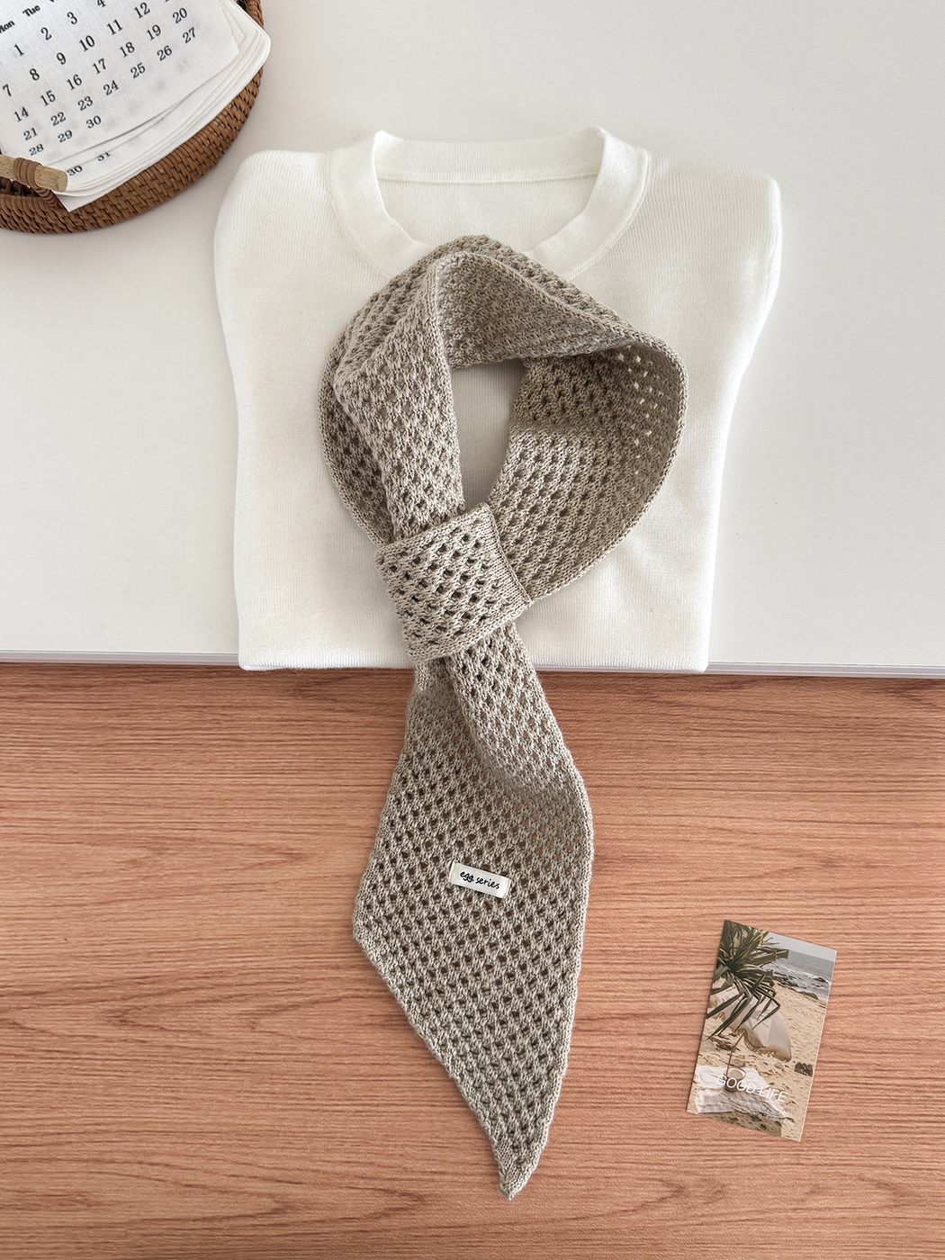 Cream openwork pull-through scarf displayed with a folded white top
